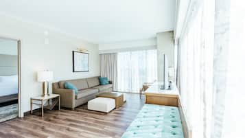 Ein modernes Hotelzimmer mit einer Couch, einem Couchtisch, einem Schreibtisch und einem großen Fenster.