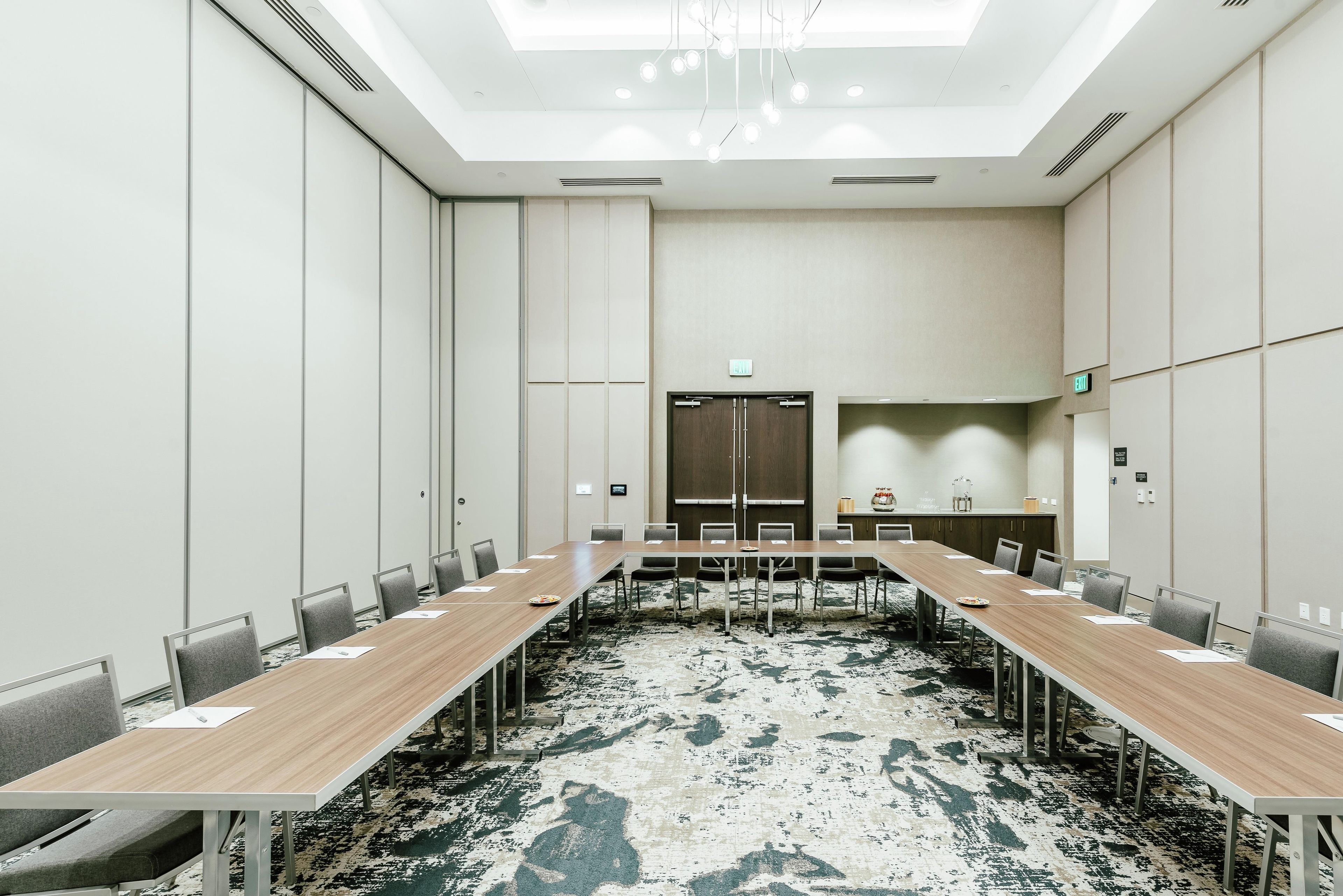 A conference room with a long table, chairs, a patterned carpet, and a ceiling with recessed lighting.