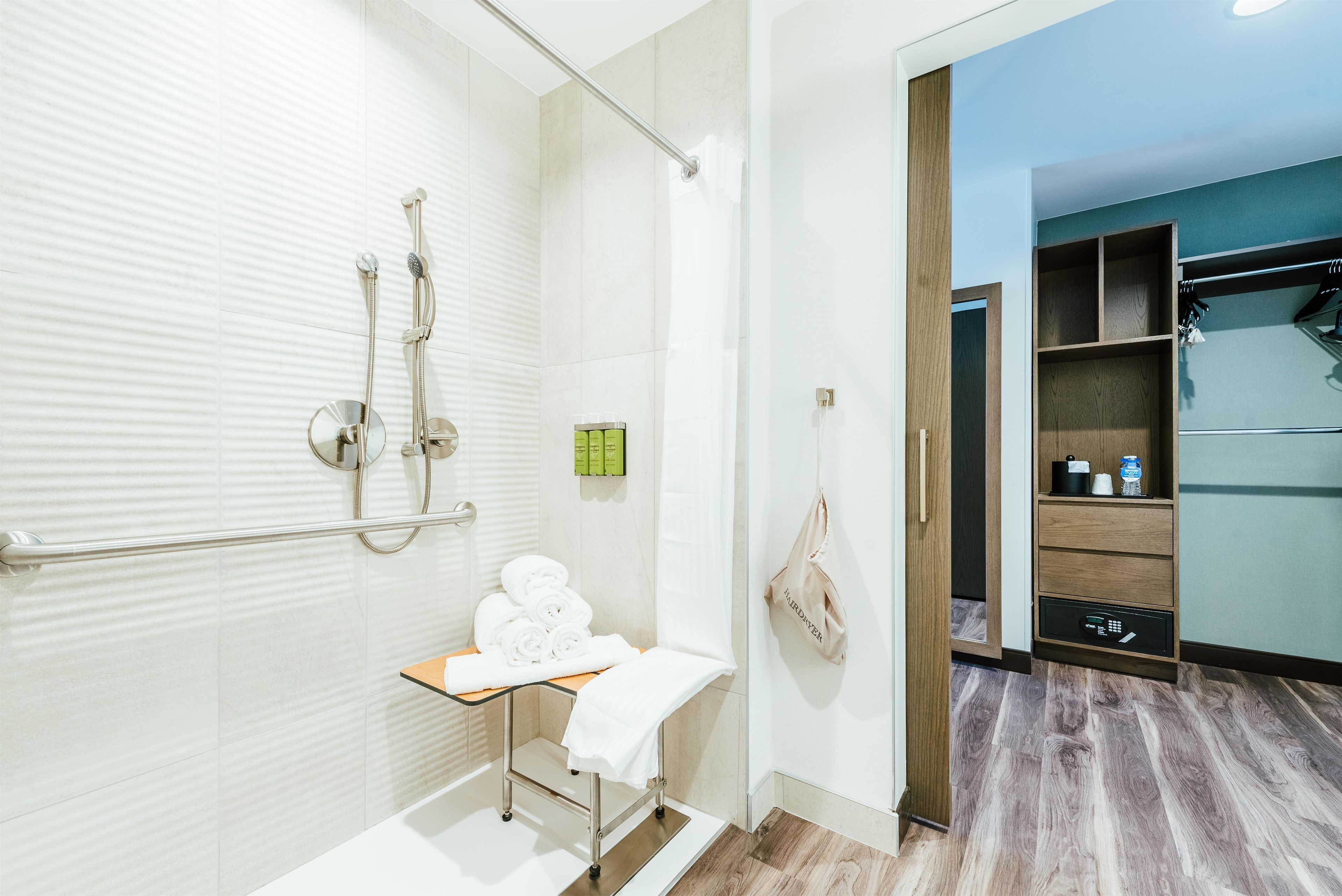 A modern bathroom with a shower, a towel rack, and a small shelf with toiletries.