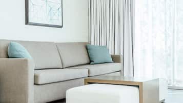 Una sala de estar moderna con un sofá color beige, dos almohadones, una mesa de centro de madera y una obra de arte abstracta enmarcada en la pared.
