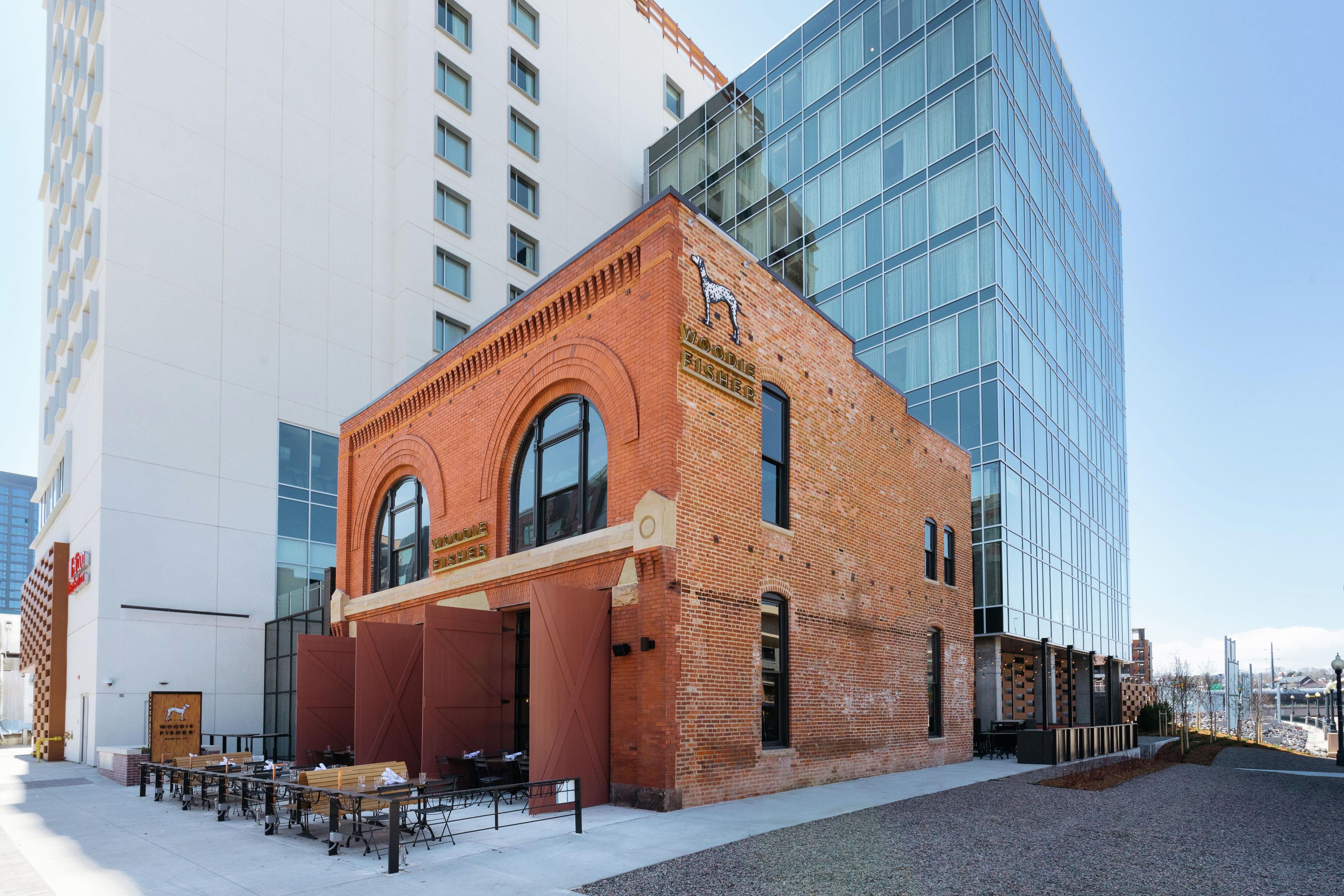 A brick building with a large arched window and a sign that reads 'Woodie Fisher.'