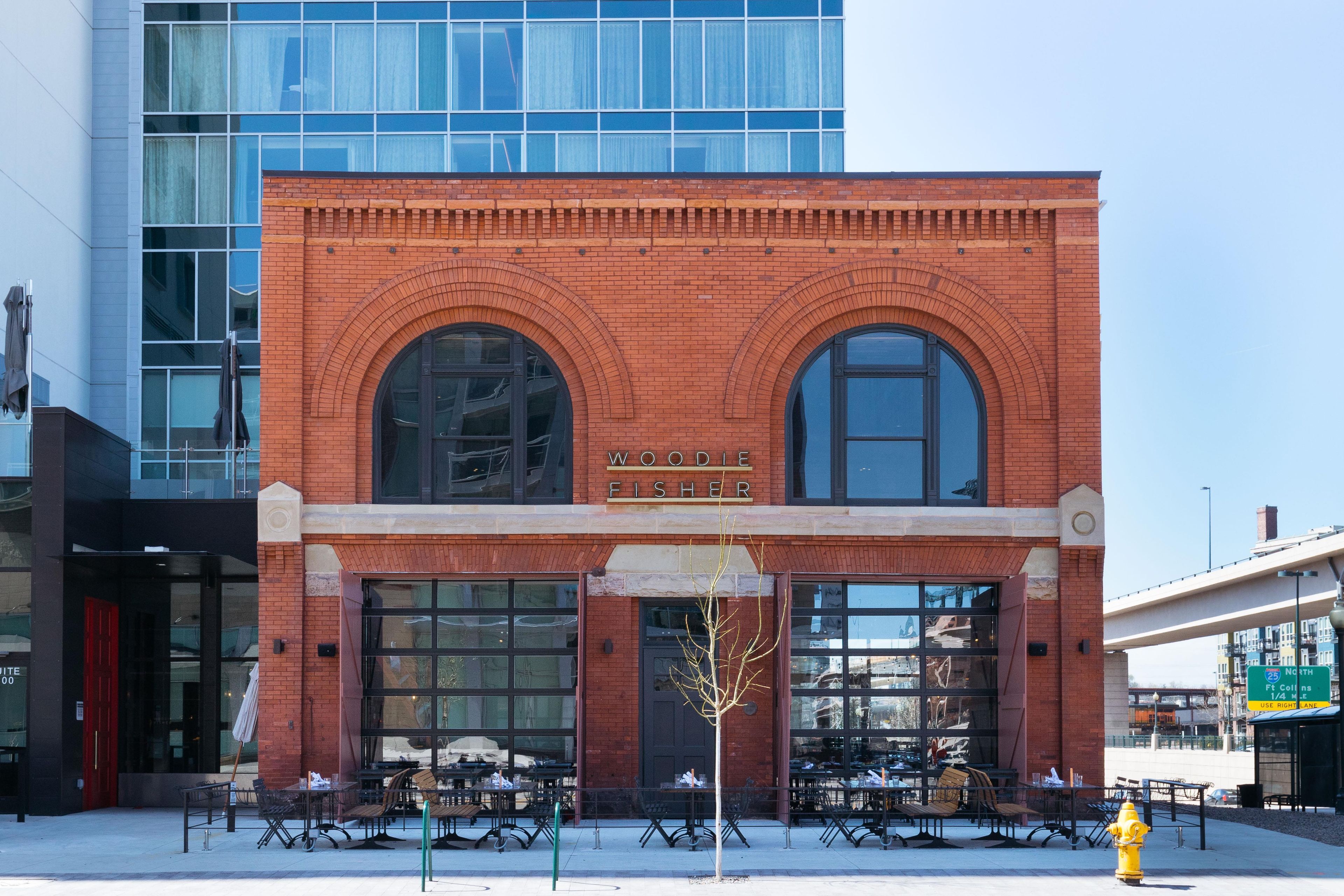 A brick building with large arched windows and a sign reading 'WOODIE FISHER'.