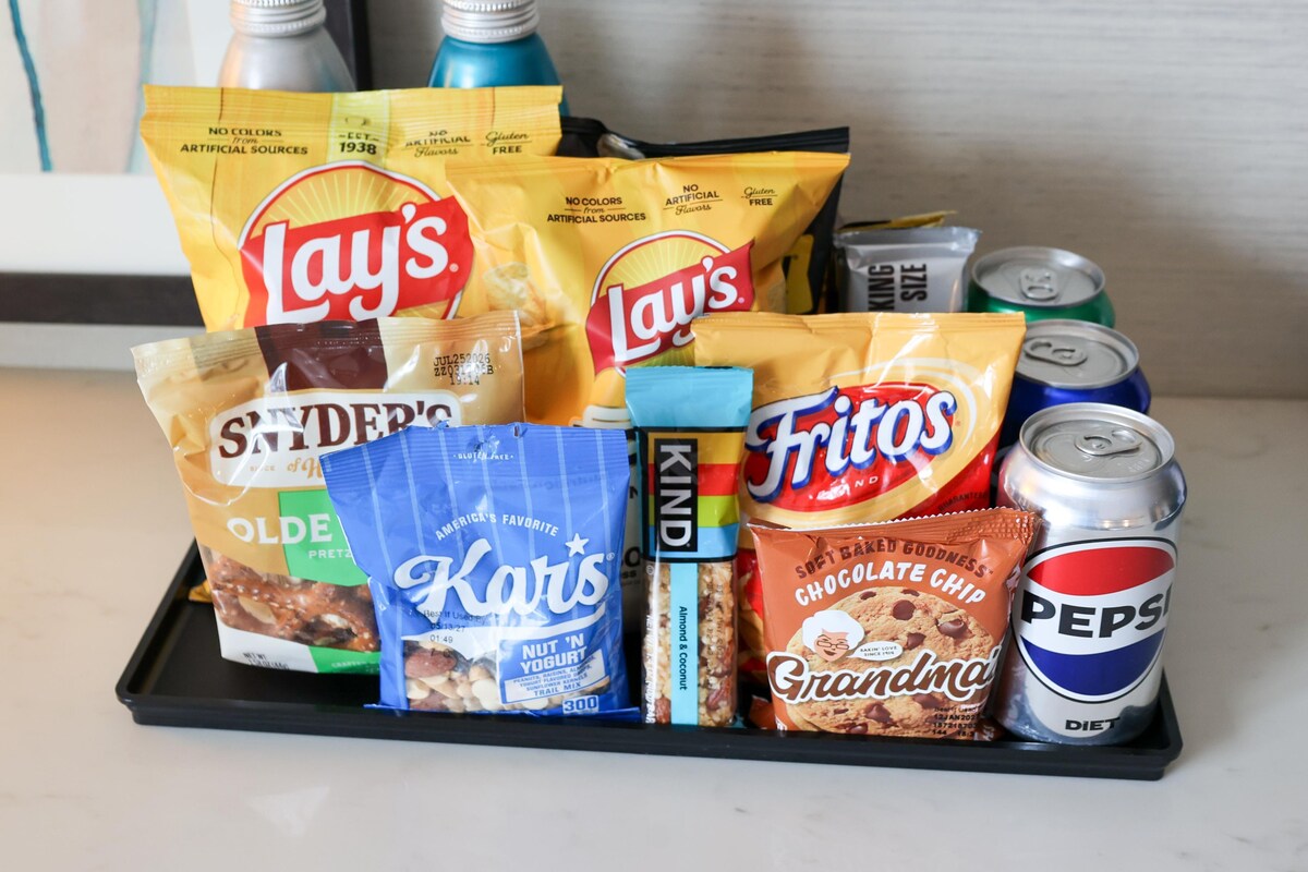 Ein Tablett mit Snacks und Getränken, darunter Lay's Chips, Pepsi und andere verpackte Lebensmittel.