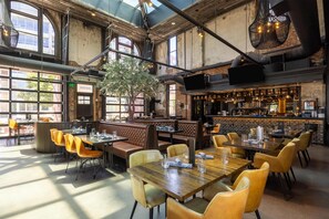 A spacious restaurant with high ceilings, large windows, and a variety of seating options including tables and booths. - Hilton Garden Inn Denver Union Station, CO (Denver)