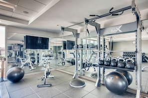 A gym with exercise equipment, mirrors, and a weight rack.