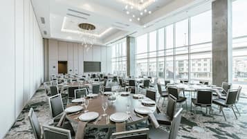 Un amplio salón de conferencias con mesas redondas, sillas y una lámpara de araña moderna.