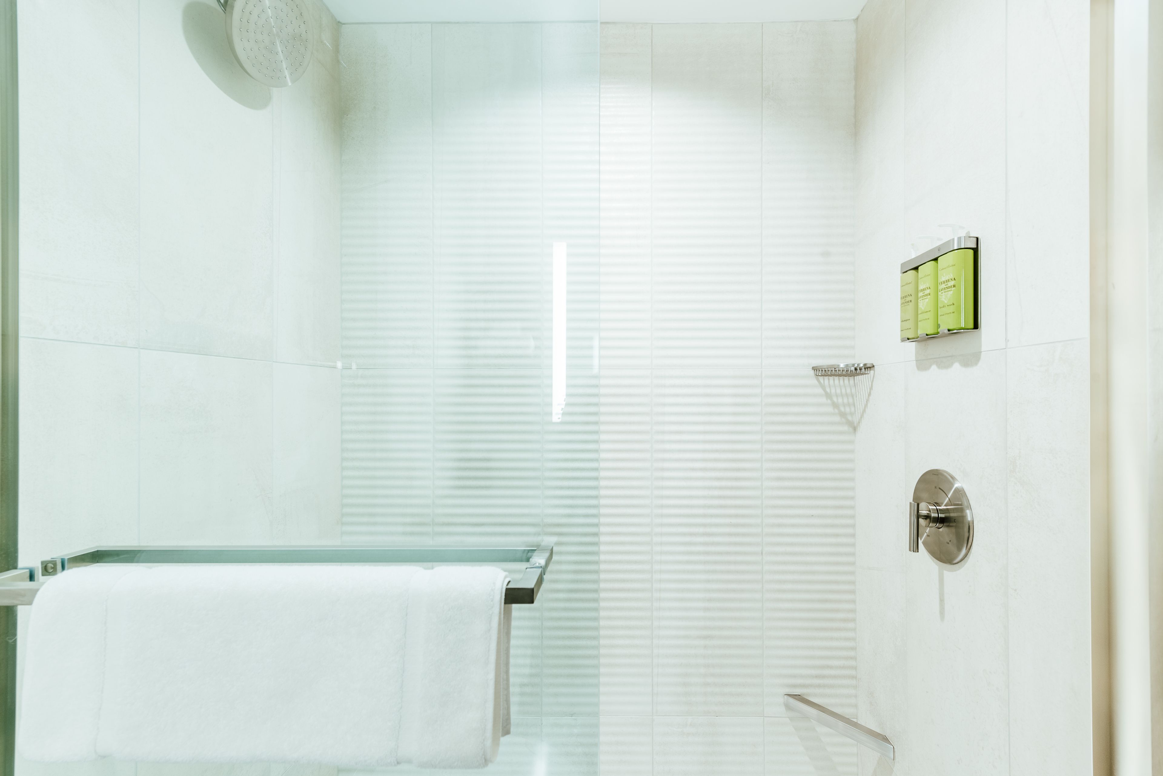 A modern bathroom with a glass shower enclosure, a glass bathtub, and a towel rack.