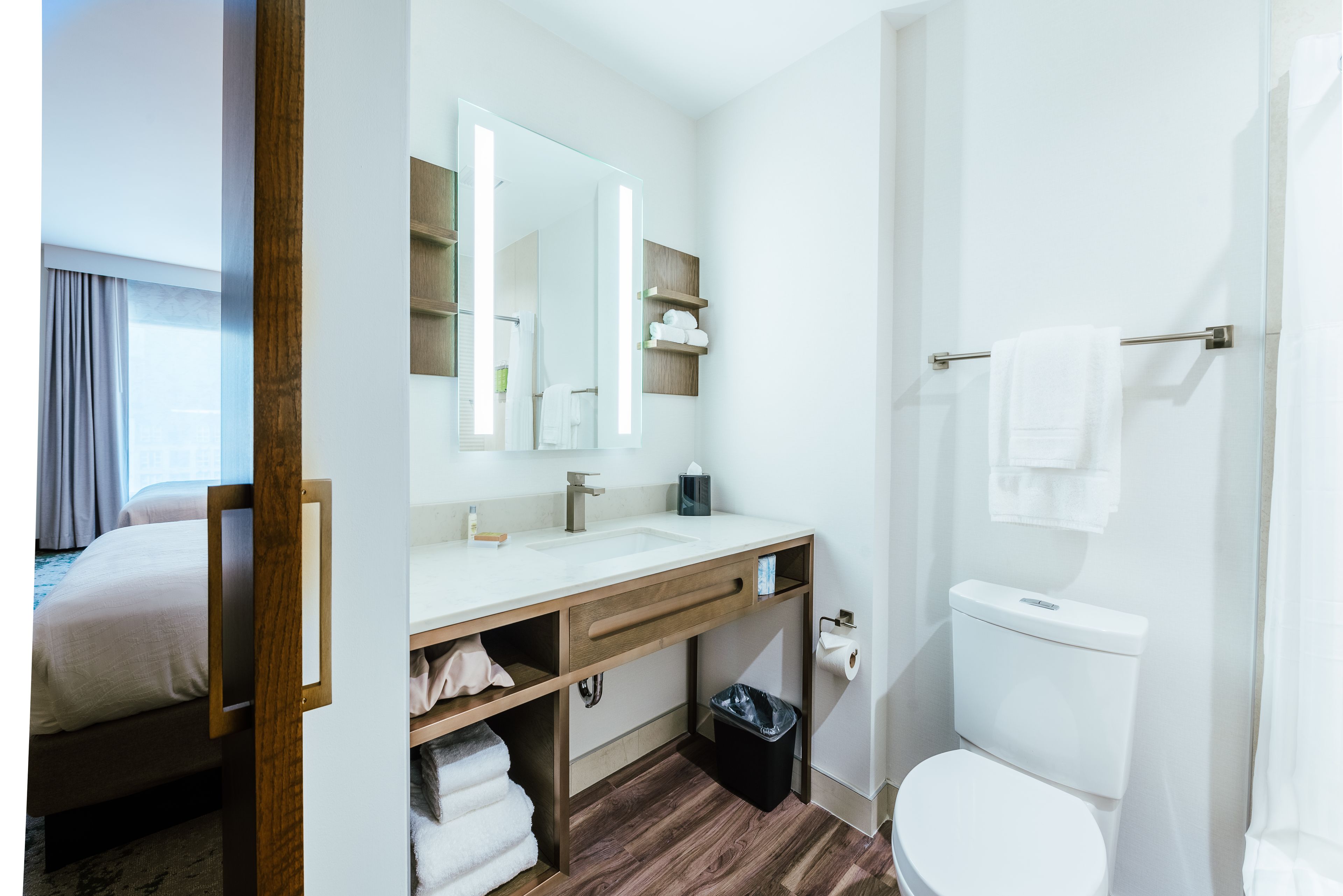 Une salle de bain moderne avec un meuble-lavabo en bois, un grand miroir, des toilettes et un espace douche.