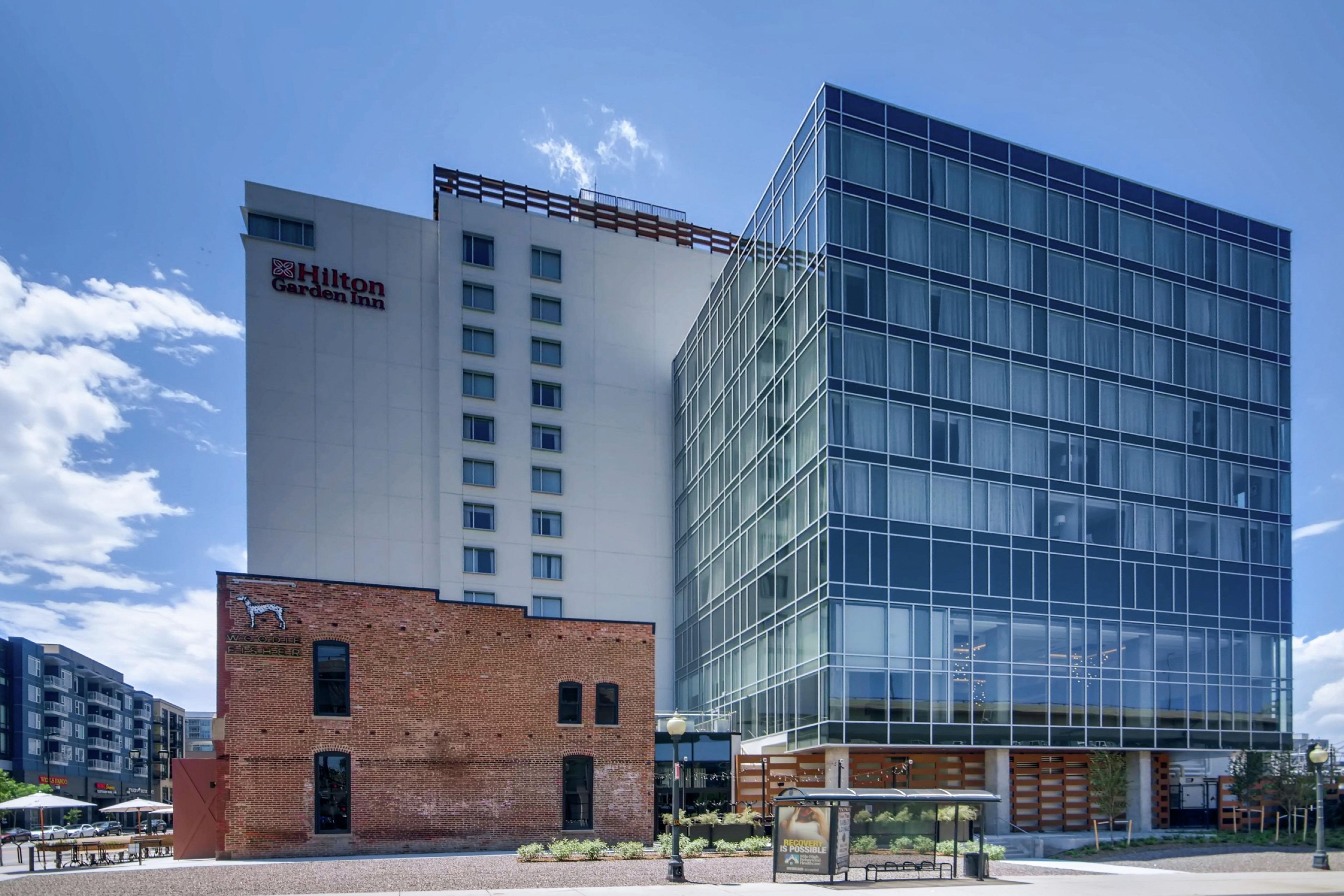 Un bâtiment moderne, avec une enseigne « Hilton Garden Inn », une façade en briques et une structure en verre.