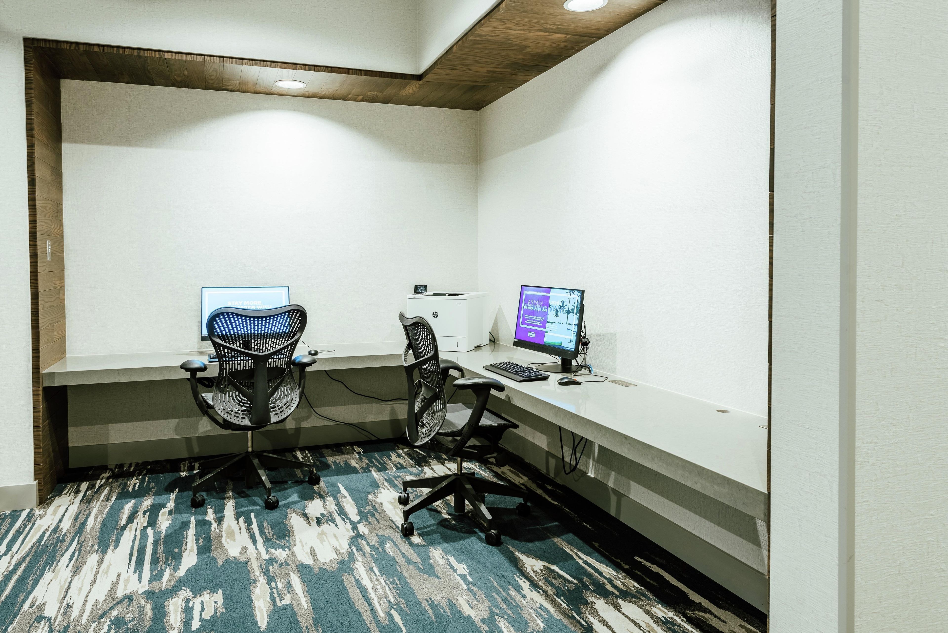 A small office space with two desks, each with a computer and chair.