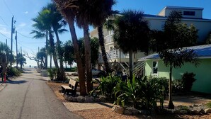 A street lined with palm trees and a green building with a signboard. - Charming Old Florida Beach Cottage with Gulf View - Just 60 Steps to Beach! (Manasota Key)