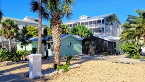 A beachfront property with multiple buildings, including a large house with a balcony and a smaller utility shed. - Charming Old Florida Beach Cottage with Gulf View - Just 60 Steps to Beach! (Manasota Key)