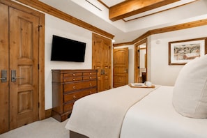 Una camera da letto con un letto, un armadio in legno, una televisione e un quadro appeso al muro.
