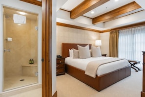 A bedroom with a large bed, wooden headboard, bedside tables, a nightstand, a lamp, and a shower area. - Willows 101 | Luxury 2BR Vail Village (Vail)
