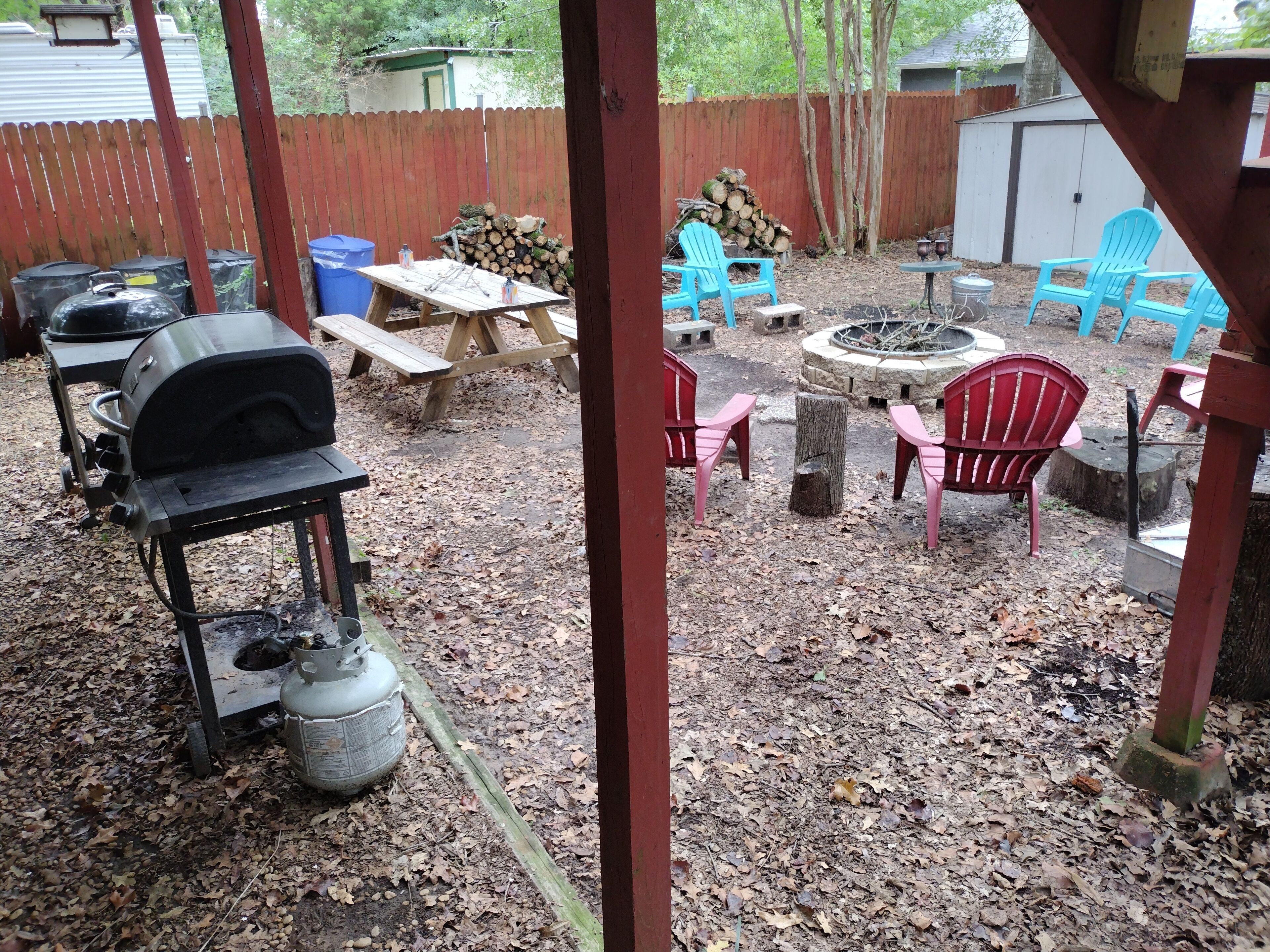 A backyard with a barbecue grill, picnic table, fire pit, and outdoor seating.