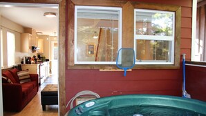 Un salón con un sofá rojo, una mesa de centro de madera y un ventanal con vistas a árboles.