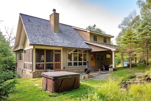 A two-story house with a sloped roof, large windows, and a covered porch area.