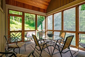 A sunroom with large windows, a glass table, and several chairs.