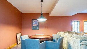Una habitación con una mesa redonda, sillas azules, un sofá y una lámpara colgante.