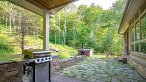 Un patio exterior con una parrilla, un horno de leña y una zona con suelo de piedra.