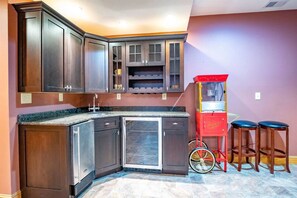 A kitchen with dark wood cabinets, a built-in dishwasher, and a red popcorn machine.