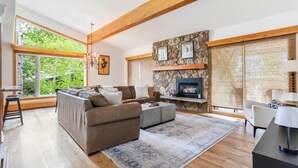 A modern living room with a fireplace, large windows, and a stone accent wall. - Riva Ridge 735 | 4BR Vail Village (Vail)