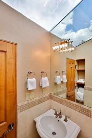 Une salle de bain avec un grand miroir, un lavabo et des portes en bois.
