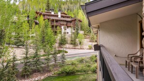 A mountain lodge with a balcony overlooking a road and forest. - Riva Ridge 735 | 4BR Vail Village (Vail)