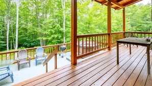 Um deck de madeira com mesa e cadeiras, com vista para uma área arborizada.