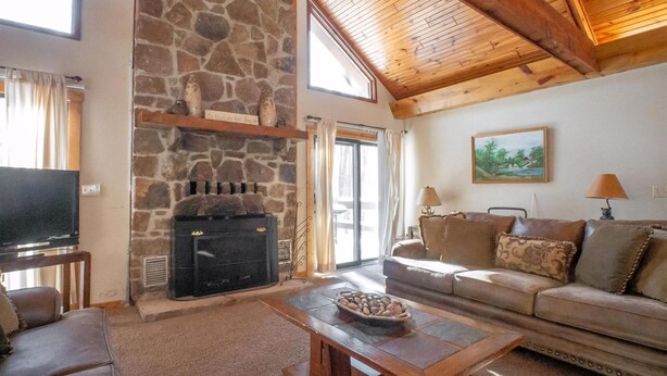 A cozy living room with a stone fireplace, a television, a sofa, and a coffee table.