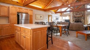 A spacious kitchen with wooden cabinets, a central island, and a stone fireplace.