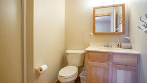 Et badeværelse med toilet, vask og spejl.