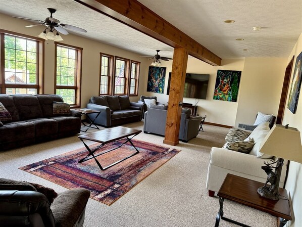 A spacious living room with a large window, a ceiling fan, and a fireplace.