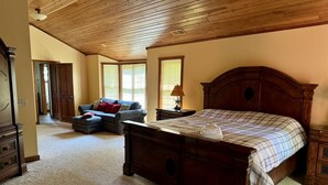 A bedroom with a large bed, a dresser, and a sofa.