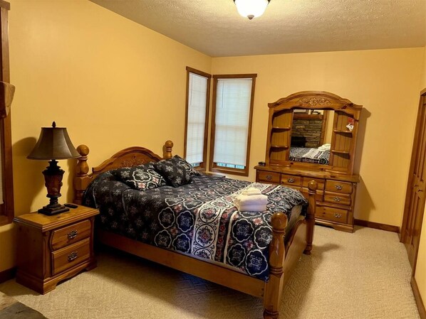 A bedroom with a bed, nightstand, dresser, and a mirror.