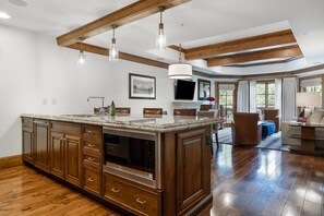 Une cuisine spacieuse dotée de meubles en bois, d’un grand îlot central et d’un coin repas avec un canapé et des chaises.