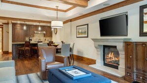 A modern living room with a fireplace, leather furniture, and a kitchen in the background.