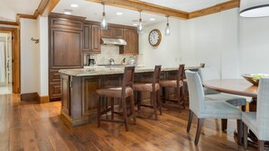 A kitchen with wooden cabinets, a large island, bar stools, and a dining table with chairs.