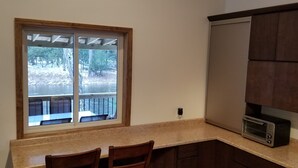 Una cocina con ventana, microondas empotrado y armarios de madera.