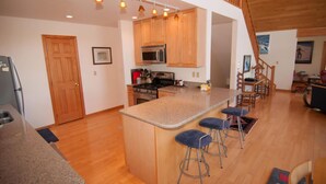 A modern kitchen with wooden cabinets, a granite countertop, and a central island with bar stools.