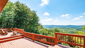 Una terraza de madera con mobiliario exterior y vistas a un paisaje verde.