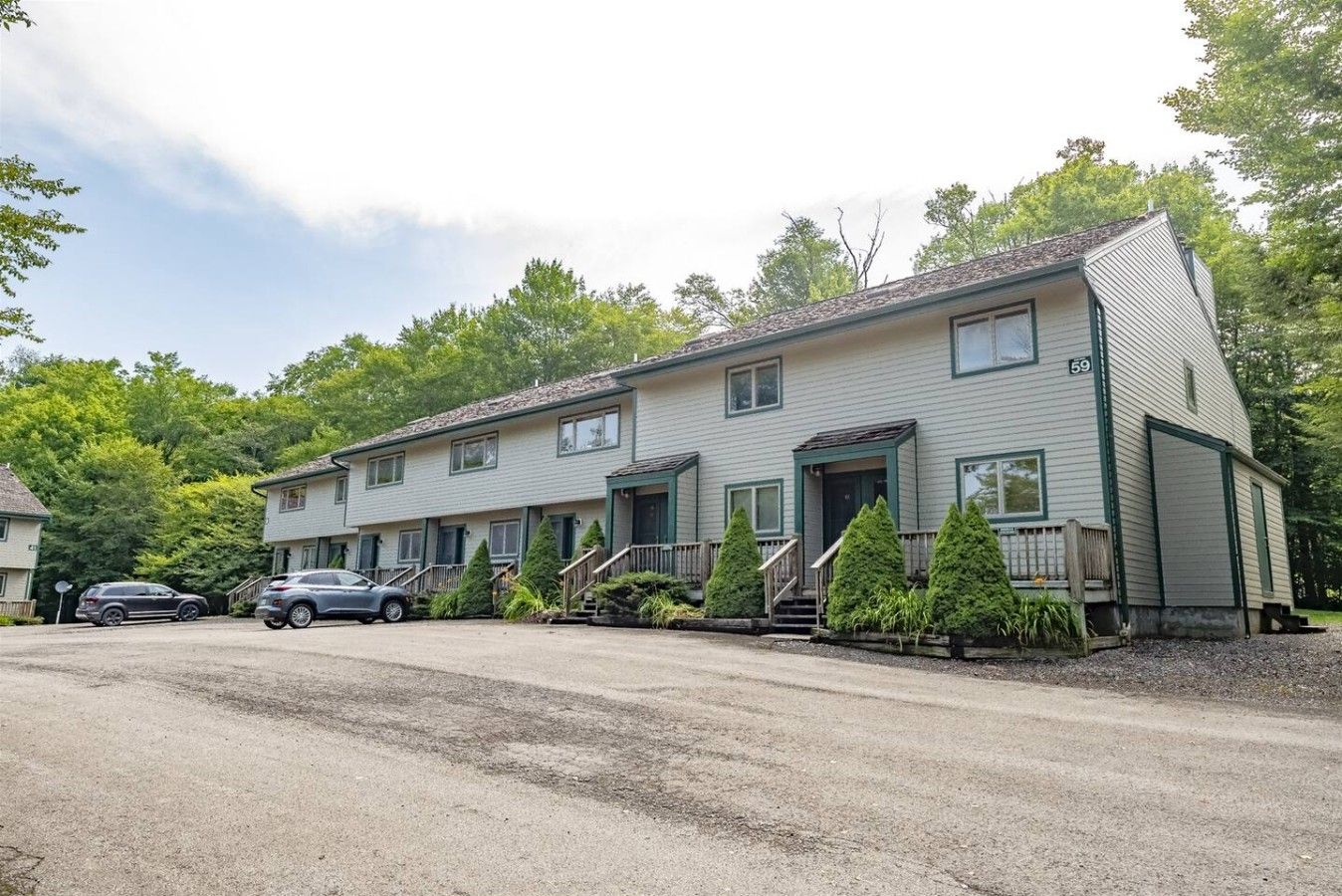 A two-story building with a front porch, a driveway, and a parking area.