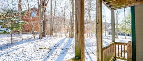 A wooden deck with a view of a snowy landscape and bare trees.