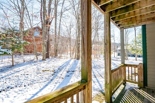 A wooden deck with a view of a snowy landscape and bare trees.