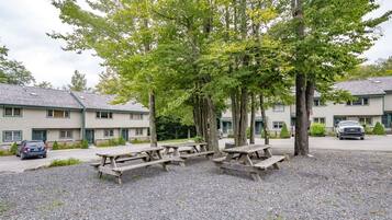 A row of picnic tables in a gravel area with a building in the background.