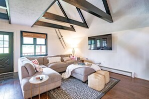 Een moderne woonkamer met een hoekbank, een ronde salontafel en een vloerkleed met een patroon.