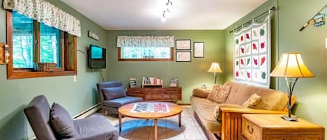 A cozy living room with a sofa, armchair, coffee table, and a television.