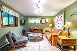 Ein gemütliches Wohnzimmer mit einer Couch, einem Sessel, einem Couchtisch und einem Fernseher.