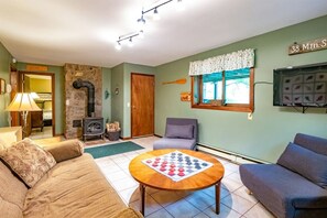 A cozy living room with a fireplace, a sofa, a chair, and a table with a board game.