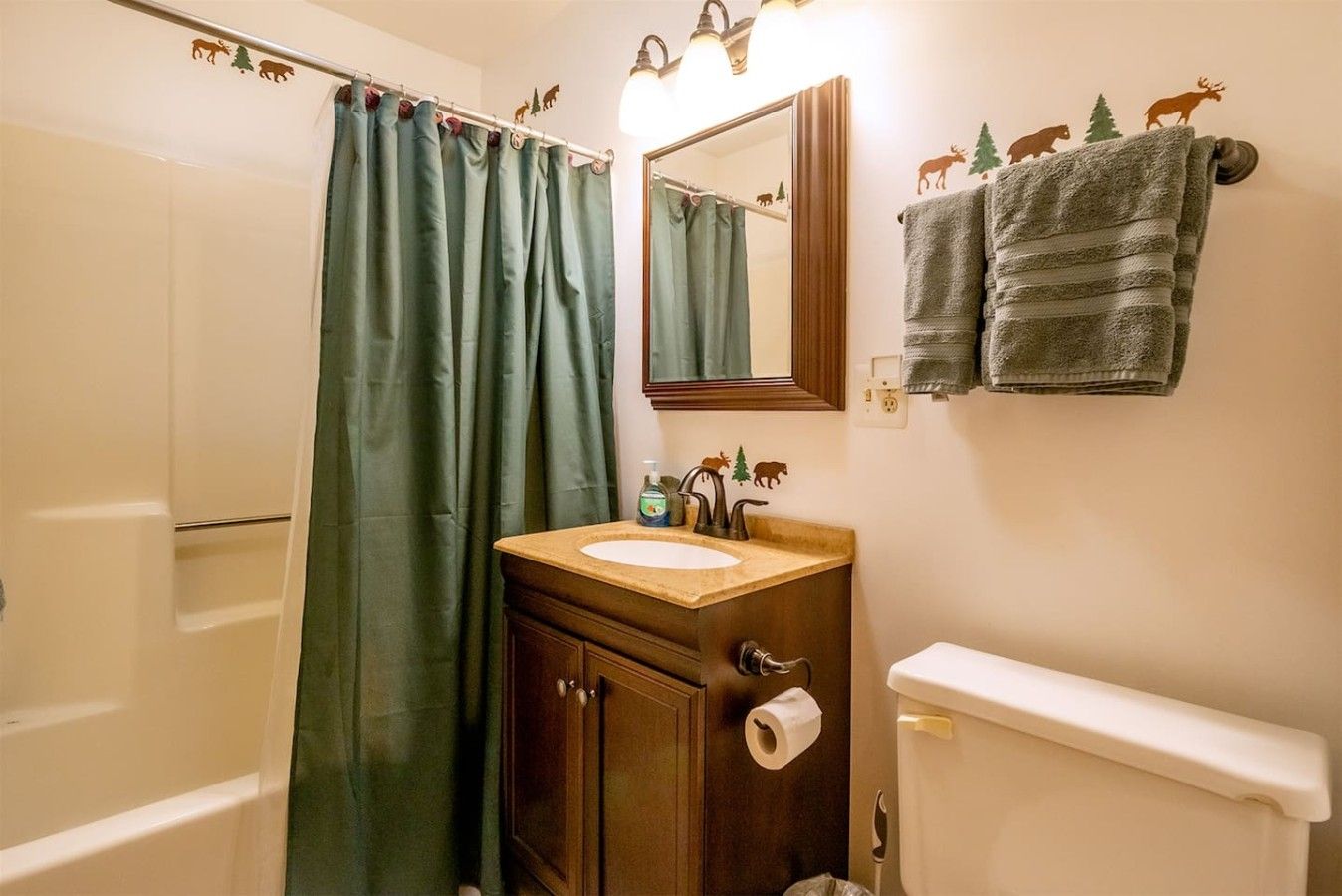 Ein Badezimmer mit einem Holzwaschtisch, einem Spiegel, einer Toilette und einer Duschvorhang.